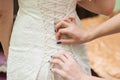 Bridesmaids dress laces on the back of a bride Royalty Free Stock Photo