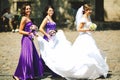 Bridesmaids help bride to put on earrings and necklace