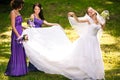 Bridesmaids help bride to put on earrings and necklace