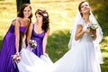 Bridesmaids help bride to put on earrings and necklace