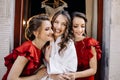 Bridesmaids look in each other eyes standing before smiling brid