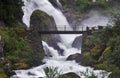 Bridge across the stream near a powerful waterfall