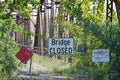 Bridge closed sign in front of dilapidated bridge with overgrowth of trees and bushes