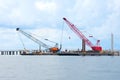 Bridge construction with crawler cranes on flat boats floating on water
