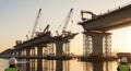 Bridge Construction Site with Cranes and Heavy Machinery Over Water at Sunset Architectural Engineering Project Royalty Free Stock Photo