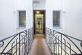 Bridge corridor of a house with wrought iron balustrades and access to an elevator with a metal and glass structure