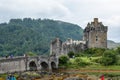 The bridge leading to Eilean Donan Castle, Scotland, UK with a lot of visiting tourists in typical Scottish cloudy weather Royalty Free Stock Photo