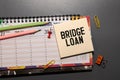bridge loan. light wooden background. with text on notepad Royalty Free Stock Photo
