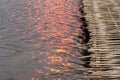 Bridge made of bamboo strips over wavy water surface with glittering orange sun light.