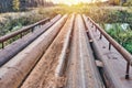 Bridge of old metal pipes over tranquil river at rural site Royalty Free Stock Photo