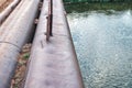 Bridge of old metal pipes over tranquil river at rural site Royalty Free Stock Photo