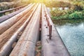 Bridge of old metal pipes over tranquil river at rural site Royalty Free Stock Photo