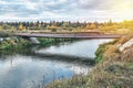 Bridge of old metal pipes over tranquil river at rural site Royalty Free Stock Photo