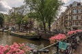 Bridge over canal with flowers, bicycles, old buildings and boats in Amsterdam. Royalty Free Stock Photo