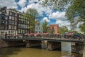 Bridge over canal with old buildings, people and cyclists passing by in Amsterdam.