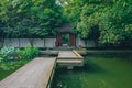 Bridge over pond leading to a doorway under trees, in a Chinese garden, near West Lake, Hangzhou, China Royalty Free Stock Photo