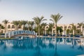 Bridge over the pool with turquoise water at the resort. Rows of empty chaise-lounges near the swimming pool at the hotel