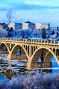A bridge over a river with snow on the trees and buildings in the background Royalty Free Stock Photo