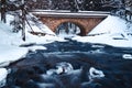 Bridge over river in winter, surrounded by forest and snow Royalty Free Stock Photo