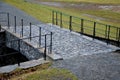 Bridge over safety spillway of the dam. stone bridge with natural paving of gray flat stones. on the edge of the retaining walls i Royalty Free Stock Photo