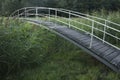 A bridge for pedestrians over a small creek at the forest edge Royalty Free Stock Photo