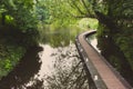 Bridge in the park faded. Walkway over water in forest filtered. Curve path over pond in summer park. Peaceful place. Royalty Free Stock Photo