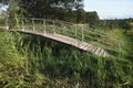 A bridge for pedestrians over a small creek at the forest edge Royalty Free Stock Photo