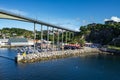 Bridge surrounded by boats and rocks covered in greenery and houses in Norway