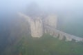 Bridge and towers of the Koporye fortress in dense morning fog Royalty Free Stock Photo