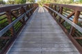 Bridge with wood deck and rusty metal railing over a lake with grassy shore