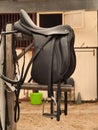 Bridle and professional dressage saddle hanging near stable