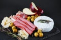 Brie cheese with salami, bacon, parmesan, olives, cut red apple and rosemary Royalty Free Stock Photo