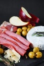 Brie cheese with salami, bacon, parmesan, olives, cut red apple and rosemary Royalty Free Stock Photo