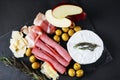 Brie cheese with salami, bacon, parmesan, olives, cut red apple and rosemary Royalty Free Stock Photo