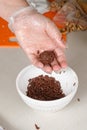 Brigadeiro brigadier in a confectioner`s hand next to a jar of chocolate sprinkles