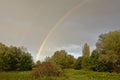 Brigh colorful rainbow on a grey sky over over trees in a marshlald landscape with trees Royalty Free Stock Photo