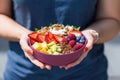 a bright acai bowl with mixed fruits held in the hand