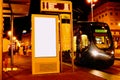 Night scene at tram stop with blank advertising panel