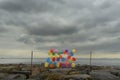 Bright airy balls of different colors on the rocky shore overlooking the gloomy sky