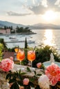 Bright Aperol Spritz cocktails with sunset Mediterranean coastline as a backdrop.