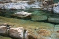 Bright aqua colored water flowing over colorful rocks and boulders at a local waterfall. Royalty Free Stock Photo