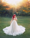 Bright art photo, cute large plump tender girl with red hair in long silver light dress with white train stands in Royalty Free Stock Photo