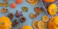 Bright autumn background. Top view of a white and brown checked kitchen towel, orange pumpkin, yellow squash, autumn leaves,