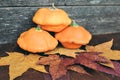 Autumn composition of three orange pumpkins and leaves on a wooden background