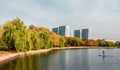 Bright autumn landscape of a city Park in Moscow with willows on the Bank and the silhouette of a man on the SUP board Royalty Free Stock Photo