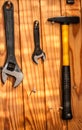 A bright background with two steel spanners and a hammer hanging on a wooden wall