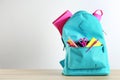 Bright backpack with different school stationery on wooden table against white background. Royalty Free Stock Photo