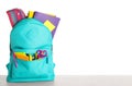 Bright backpack with school stationery on stone table against white background Royalty Free Stock Photo