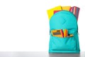 Bright backpack with school stationery on grey table against white background Royalty Free Stock Photo