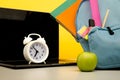 Bright backpack with supplies and laptop on a table isolated on yellow. Online education theme Royalty Free Stock Photo